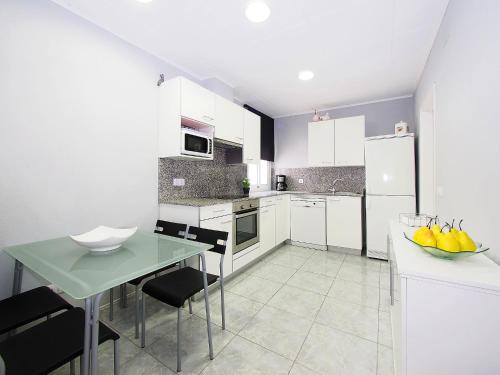 エンプリアブラバにあるHoliday Home Sant Mori by Interhomeの白いキャビネット、緑のテーブルと椅子付きのキッチンが備わります。