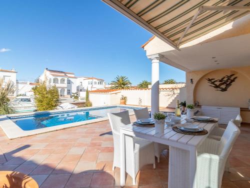a patio with a table and chairs and a swimming pool at Holiday Home Bonica by Interhome in Empuriabrava