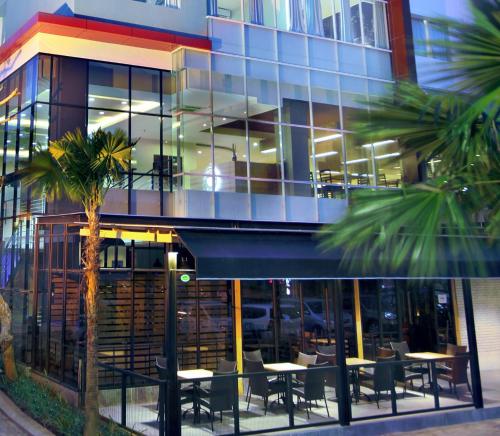 a restaurant with tables and chairs in front of a building at Hotel Neo Candi Simpang Lima - Semarang by ASTON in Semarang