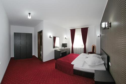 Hotel Rebis في برايلا: غرفة فندق بسرير وسجادة حمراء