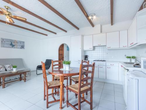 エンプリアブラバにあるApartment Las Chabolas by Interhomeの白いキャビネット、木製テーブルと椅子付きのキッチンが備わります。