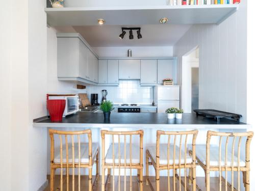 une cuisine avec des placards blancs et un comptoir avec quatre chaises dans l'établissement Apartment Caballito de Mar by Interhome, à Empuriabrava