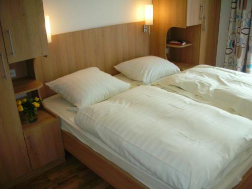a bed with white sheets and pillows in a room at Gasthof Blume in Hausach
