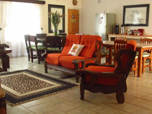 a living room with orange chairs and a table at Bhangazi Lodge Bed & Breakfast in St Lucia