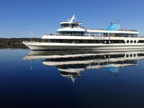 a large boat in the water with its reflection at Hotel Schloss Berg in Berg am Starnberger See