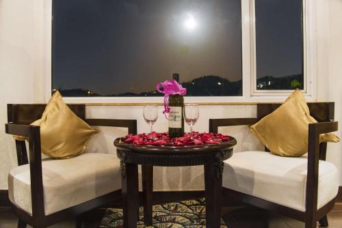 a table with two chairs and two glasses of wine at Regenta Resort MARS Valley View Shoghi in Shimla