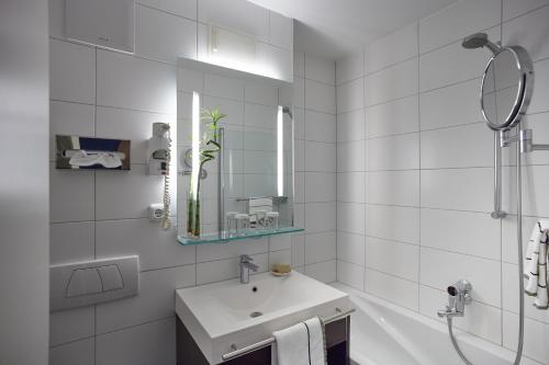 a bathroom with a sink, mirror, and bathtub at Hotel Schloss Berg in Berg am Starnberger See