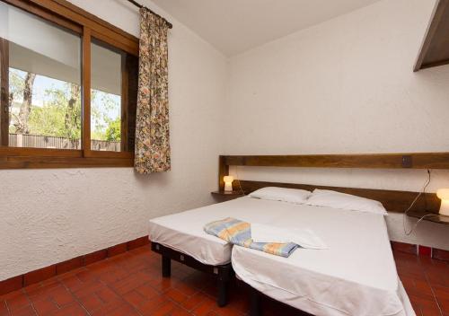 a bedroom with a white bed and a window at Villaggio Los Nidos in Lignano Sabbiadoro