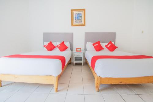 two beds in a room with red pillows at Hotel Imperial in Aguascalientes