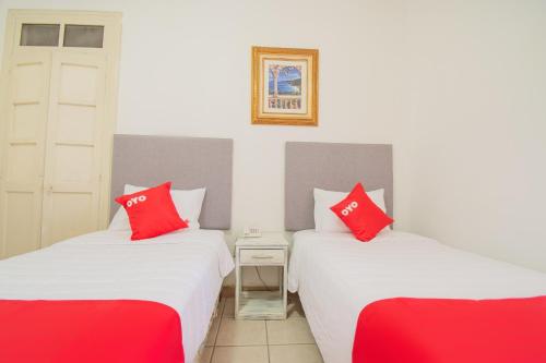 two twin beds in a room with red pillows at Hotel Imperial in Aguascalientes