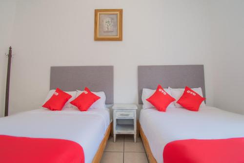 two twin beds in a room with red pillows at Hotel Imperial in Aguascalientes