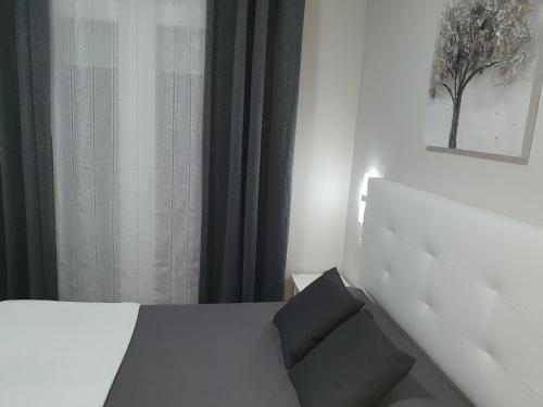 a bedroom with a white bed with a black pillow at Hostal Málaga in Arcos de la Frontera