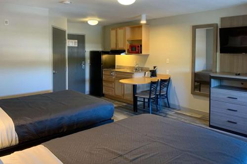 a bedroom with a bed and a kitchen with a table at Suburban Studios near Panama City Beach in Panama City