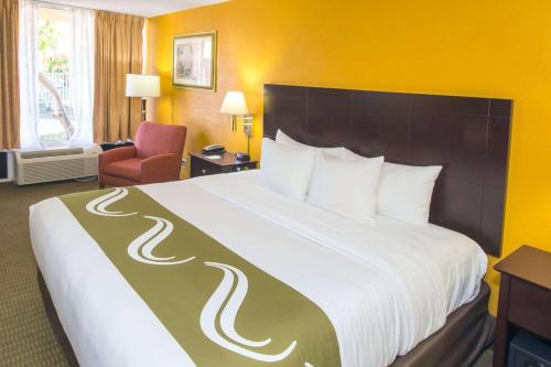 a hotel room with a large bed and a chair at Quality Inn & Suites Conference Center in New Port Richey