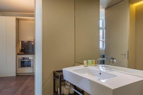 La salle de bains est pourvue d'un lavabo blanc et d'un miroir. dans l'établissement 8 Building Apartments, à Lisbonne