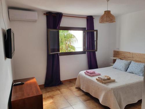 a bedroom with a bed with purple curtains and a window at Casaflor in Mojácar