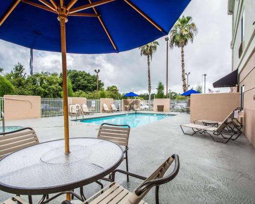a table with an umbrella next to a swimming pool at Quality Inn Plant City - Lakeland in Plant City