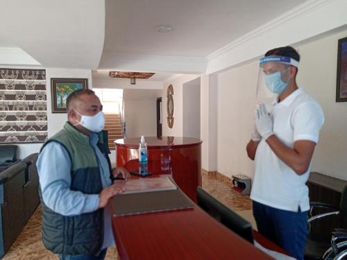 two men wearing face masks standing at a table at Regenta Resort MARS Valley View Shoghi in Shimla