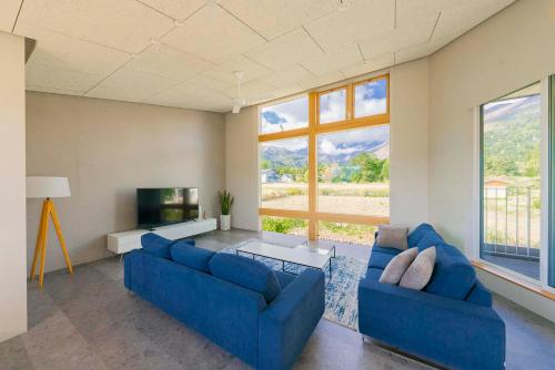 a living room with two blue couches and a tv at Echo Rocks by The Hakuba Collection in Hakuba