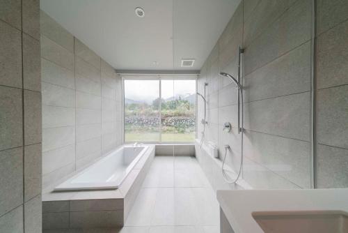 La salle de bains est pourvue d'une baignoire, d'une douche et d'une fenêtre. dans l'établissement Echo Rocks by The Hakuba Collection, à Hakuba