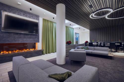 a lobby with a fireplace and a couch and chairs at Hotel Planai by Alpeffect Hotels in Schladming