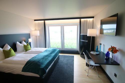 Habitación de hotel con cama y escritorio con ventana en AM Hotel by WMM Hotels en Ampfing