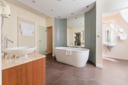 een grote badkamer met een bad en een wastafel bij La Prima Fashion Hotel Budapest in Boedapest