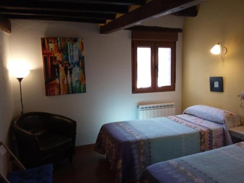 1 dormitorio con 2 camas, ventana y silla en Alborada, en Sequeros