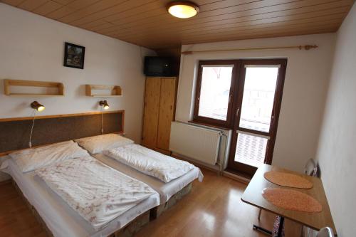 um quarto com uma cama, uma mesa e uma janela em Penzión Antónia em Habovka