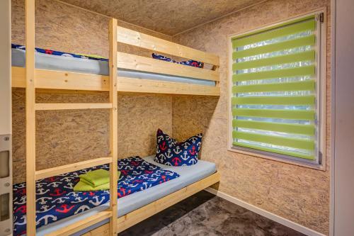 Zimmer mit Etagenbett, 2 Etagenbetten und einem Fenster in der Unterkunft Feriendorf Fynnus in Dranske