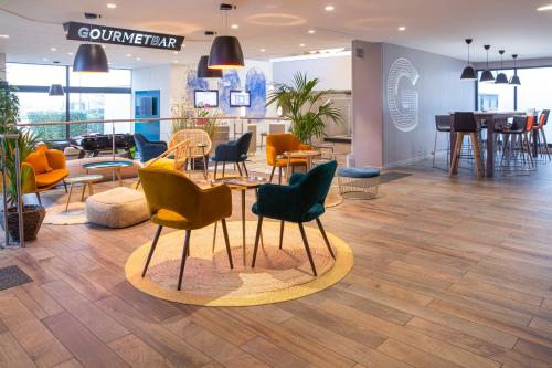a lobby with chairs and tables in a building at Novotel Roissy Saint Witz in Saint-Witz