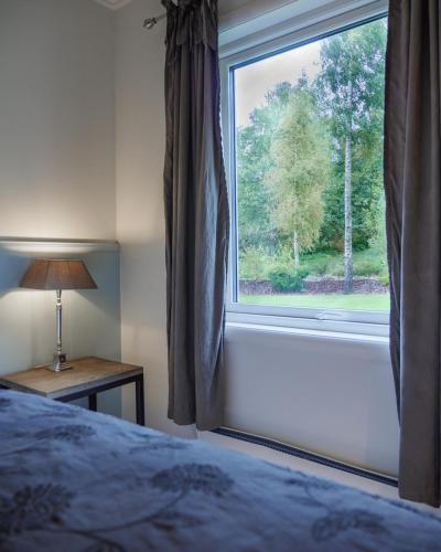 a bedroom with a window with a bed and a lamp at Strand Hotel Fevik - by Classic Norway Hotels in Fevik