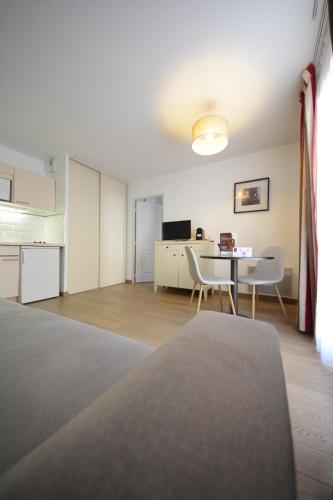 a room with a table and chairs and a kitchen at Hotel Cerise Chatou in Chatou