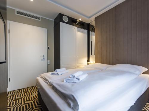 - une chambre avec un grand lit blanc et des serviettes dans l'établissement VacationClub - Baltic Park Fort Apartament F.415, à Świnoujście