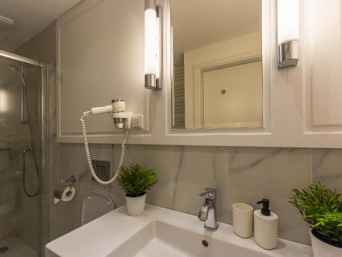 La salle de bains est pourvue d'un lavabo, d'une douche et d'un miroir. dans l'établissement VacationClub - Baltic Park Fort Apartament F.415, à Świnoujście