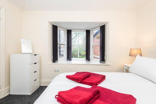 a white bedroom with two red towels on a bed at Sycamore Cottage York, dog friendly, close to the river in York