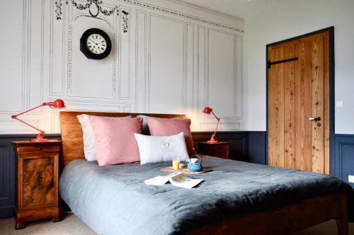 a bedroom with a bed with pink pillows and a clock at Les Ô d'Annecy in Saint-Jorioz