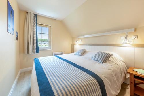 a bedroom with a large bed with blue and white stripes at Village Pierre & Vacances Belle Dune in Fort-Mahon-Plage