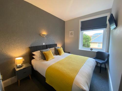 a bedroom with a bed with a yellow blanket and a window at Chelsea Hotel in Bournemouth