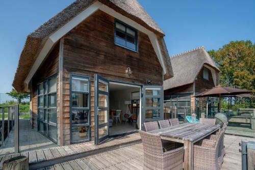 Nautic Rentals - Watervilla's Zuiderhoeve في De Heen: منزل به سطح مع طاولة وكراسي