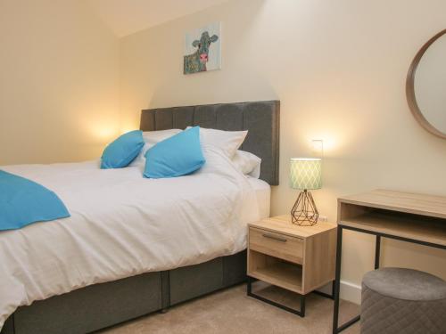 a bedroom with a bed with blue pillows and a desk at Black Lion Barn Retreat in Shrewsbury