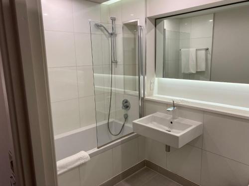 a white bathroom with a sink and a shower at Axiom Park Hotel in London