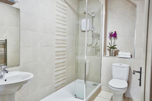 Baño blanco con aseo y lavamanos en Garrison Apartments en Fort William