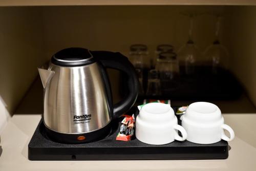 a coffee pot and two cups on a counter at Hotel LoRa in Belgrade