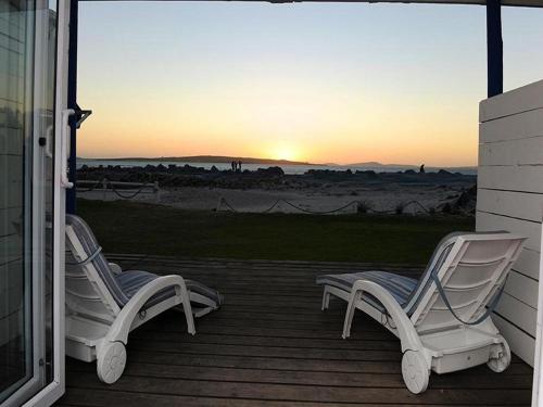 two chairs sitting on a porch watching the sunset at Friday Island in Langebaan