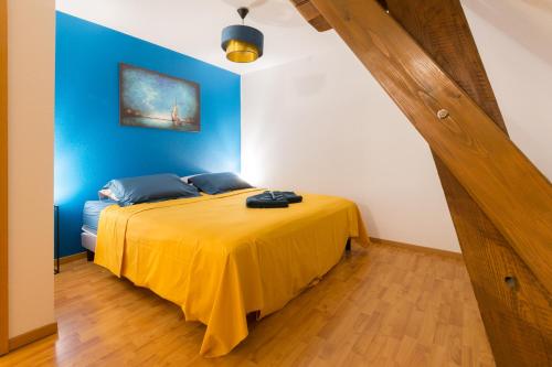 a bedroom with a yellow bed with a blue wall at Au Cocon des Cigognes in Sigolsheim