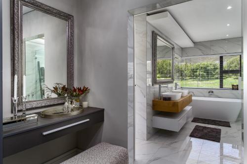 Un baño con lavabo, bañera y espejo. en Villa de luxe, en Franschhoek