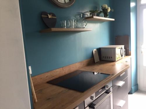 a kitchen with a counter with a microwave and a blue wall at Les Amandiers in Bouvigny-Boyeffles