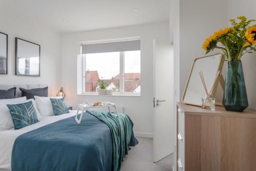 a bedroom with a bed and a vase of flowers at Luxury Serviced Apartments Stevenage, Hertfordshire in Stevenage