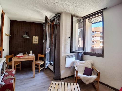 une chambre avec une table et une salle à manger avec des fenêtres dans l'établissement travelski home classic - Résidence Origanes, aux Menuires